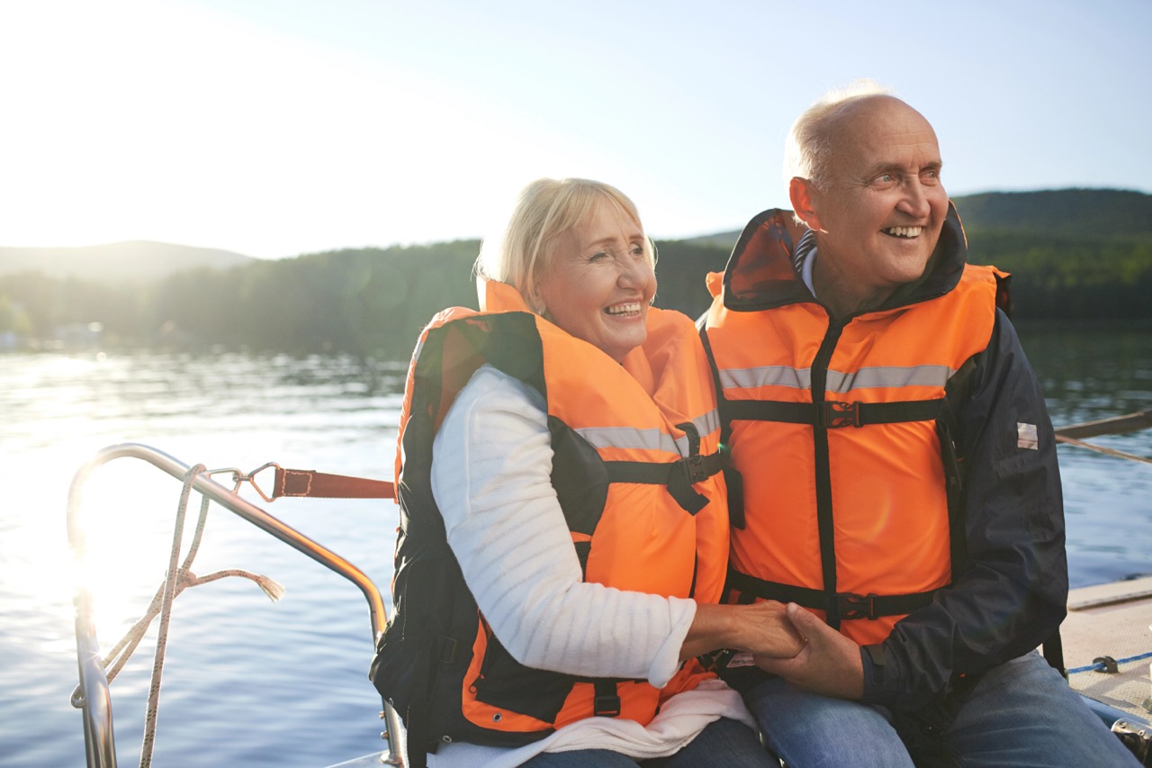 Yachting Active couple in life-vests sitting in yacht