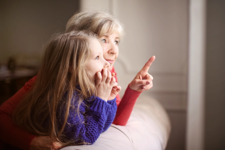 grandmother-grandchild Grandmother looks out of the window with her granddaughter